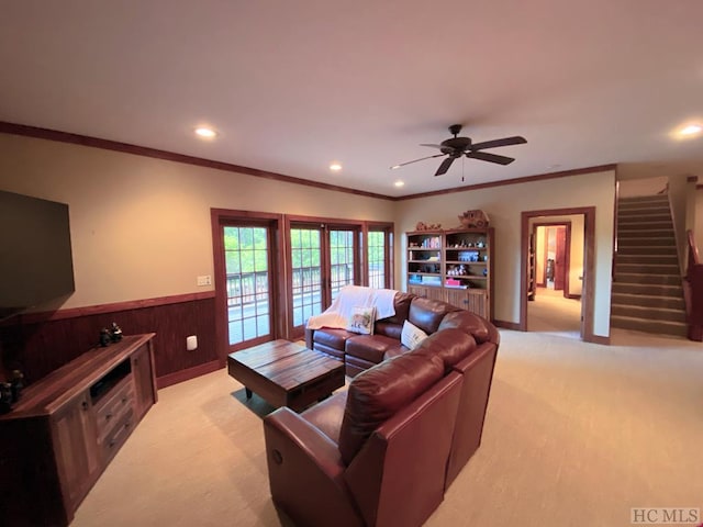 carpeted living room featuring ornamental molding, ceiling fan, and wooden walls