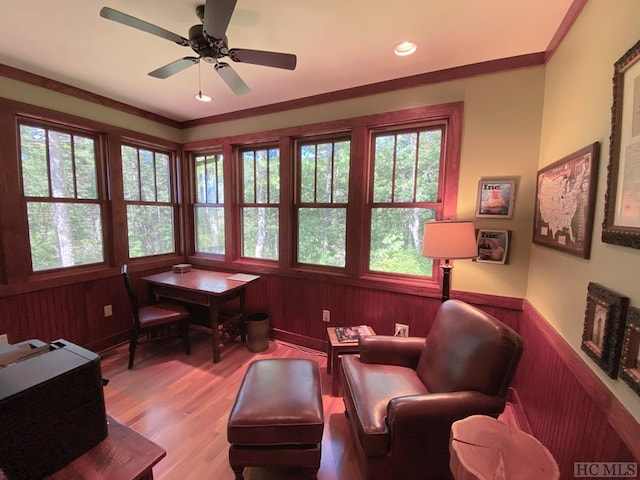 living area with ornamental molding, light hardwood / wood-style flooring, and wood walls