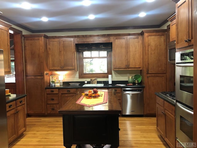 kitchen featuring sink, stainless steel appliances, a center island, and light wood-type flooring