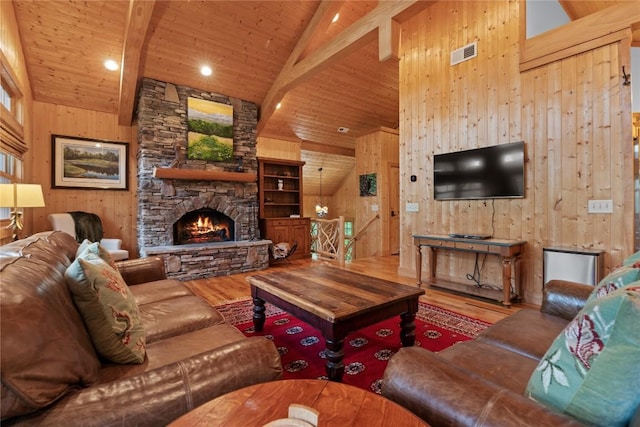living room featuring wood finished floors, high vaulted ceiling, wood walls, wood ceiling, and a stone fireplace