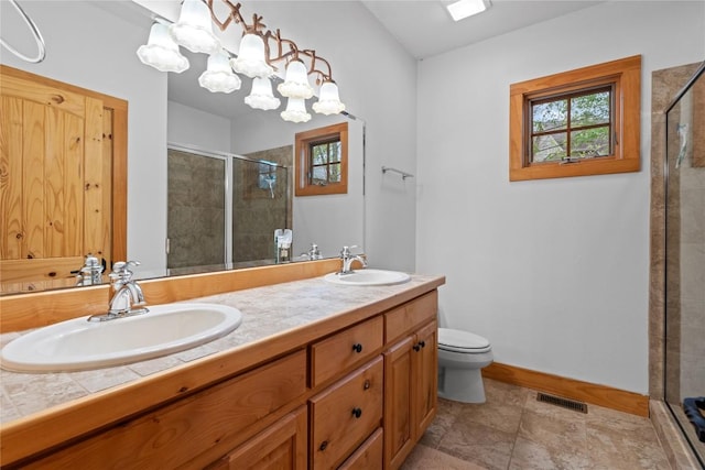 bathroom featuring a stall shower, toilet, double vanity, and baseboards