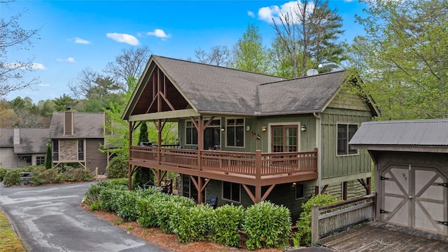 back of house with a wooden deck, a shingled roof, and driveway