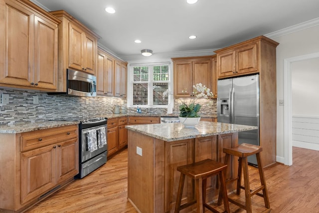 410C Highlands Cove Dr Unit 1300C, Highlands, NC 28741 - kitchen with appliances with stainless steel finishes, light wood finished floors, crown molding, a breakfast bar area, and a center island
