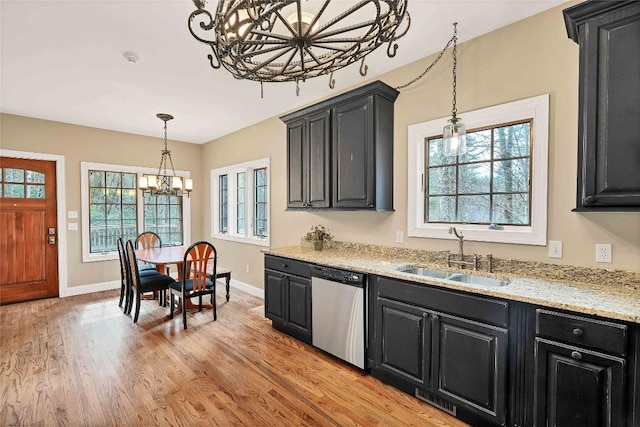 kitchen with stainless steel dishwasher, light wood-style flooring, dark cabinets, and a sink