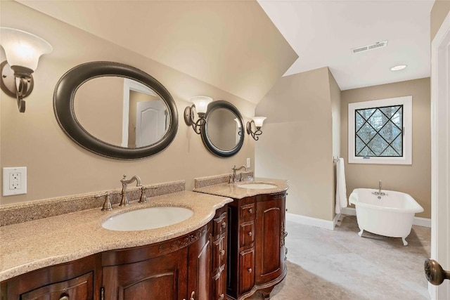 bathroom featuring a soaking tub, two vanities, a sink, and visible vents