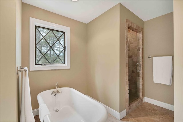 full bath with a freestanding tub, a shower stall, and baseboards