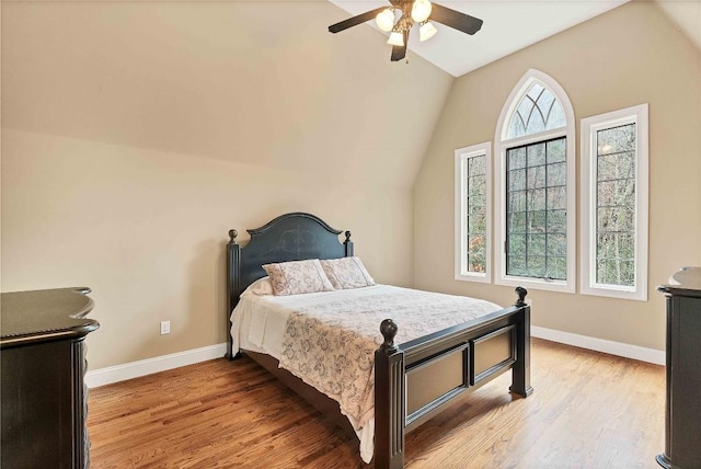 bedroom featuring light wood-style flooring, baseboards, vaulted ceiling, and a ceiling fan