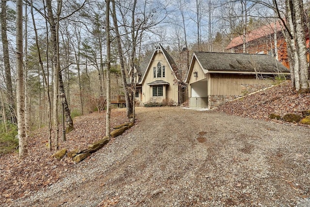 view of front facade with roof with shingles and dirt driveway