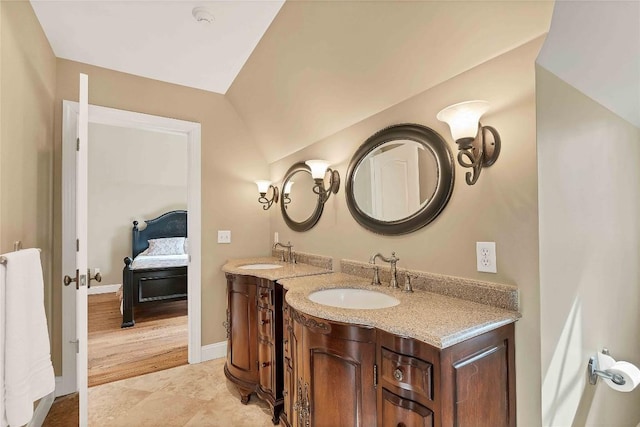 ensuite bathroom with connected bathroom, a sink, baseboards, and double vanity