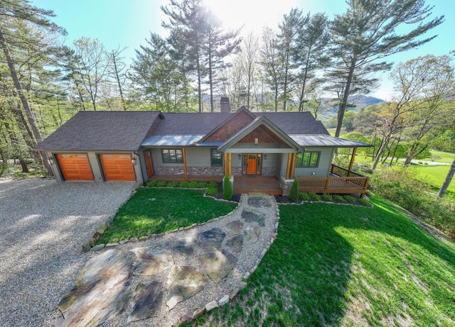 view of front of property with a front lawn, stone siding, a porch, a chimney, and driveway