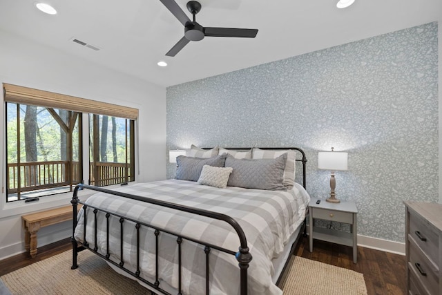 bedroom featuring baseboards, visible vents, wallpapered walls, and wood finished floors