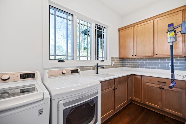 clothes washing area with washing machine and clothes dryer, a sink, dark wood-type flooring, and cabinet space