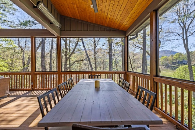 sunroom / solarium with a mountain view, a ceiling fan, and outdoor dining space