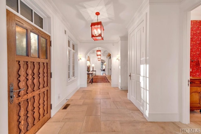 hall with ornamental molding and a chandelier