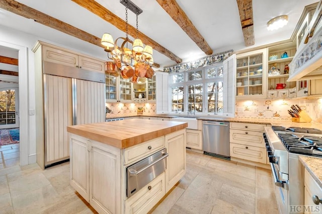 kitchen with a kitchen island, decorative light fixtures, butcher block counters, premium appliances, and beam ceiling