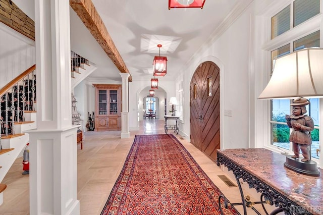 foyer featuring crown molding, beamed ceiling, and ornate columns