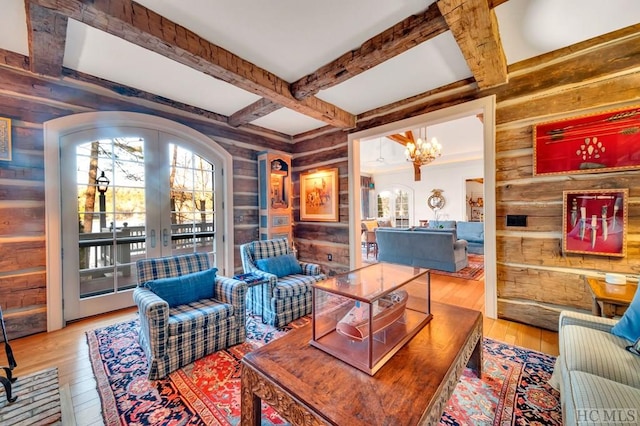 living room with hardwood / wood-style flooring, beamed ceiling, an inviting chandelier, and french doors