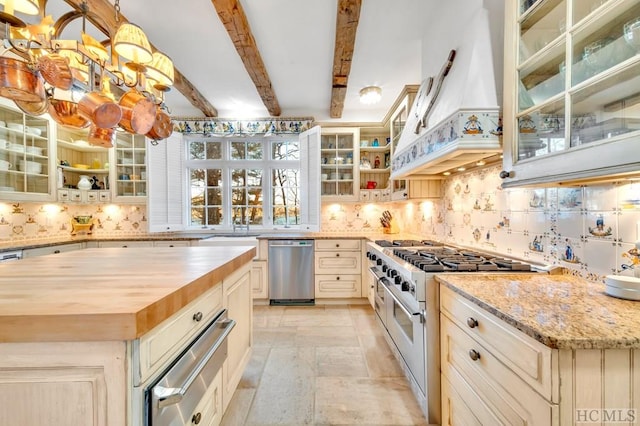 kitchen with appliances with stainless steel finishes, beam ceiling, a center island, light stone counters, and decorative light fixtures