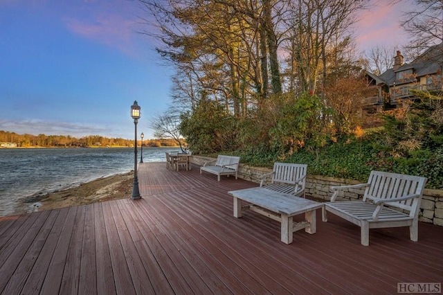 deck at dusk featuring a water view