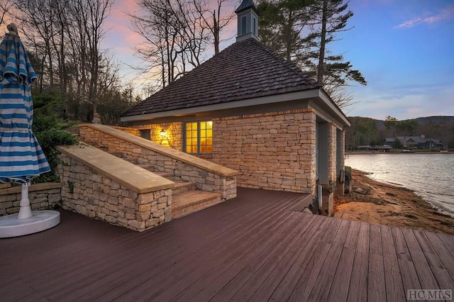 deck at dusk featuring a water view