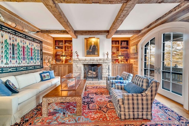 living room featuring french doors, built in shelves, hardwood / wood-style floors, beamed ceiling, and wooden walls