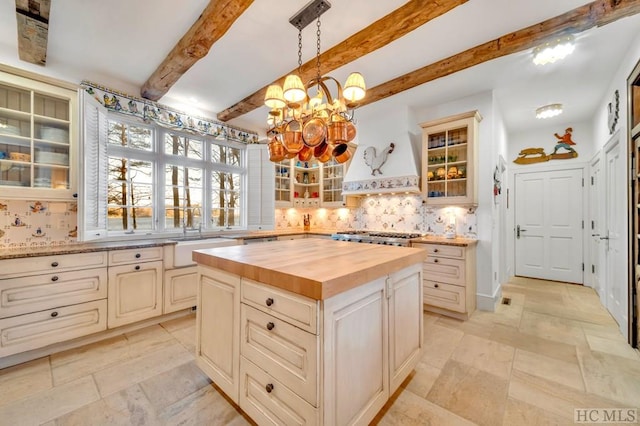 kitchen featuring butcher block counters, a notable chandelier, a kitchen island, hanging light fixtures, and decorative backsplash