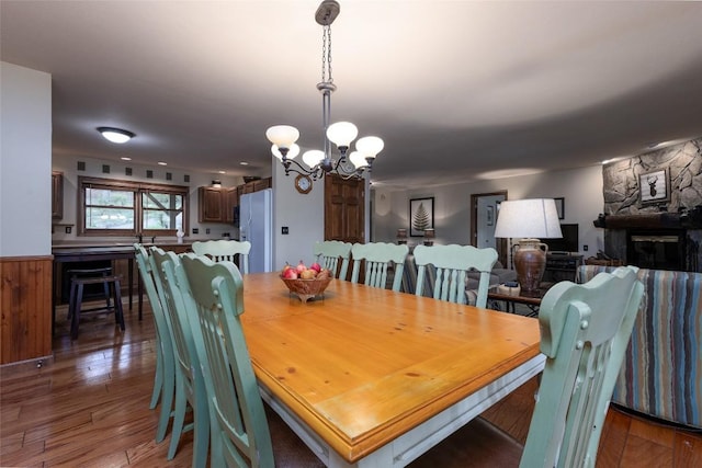 1964 Woods Mountain Trl, Cullowhee, NC 28723 - dining space featuring a chandelier, wood finished floors, a stone fireplace, and a wainscoted wall