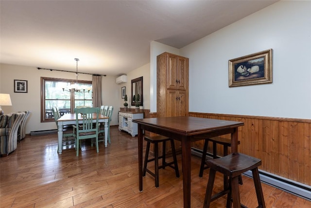 1964 Woods Mountain Trl, Cullowhee, NC 28723 - dining space featuring a wall unit AC, a chandelier, baseboard heating, light wood-style floors, and wainscoting