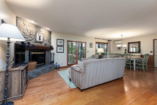 1964 Woods Mountain Trl, Cullowhee, NC 28723 - living area featuring light wood finished floors, a stone fireplace, a wall mounted AC, and a chandelier