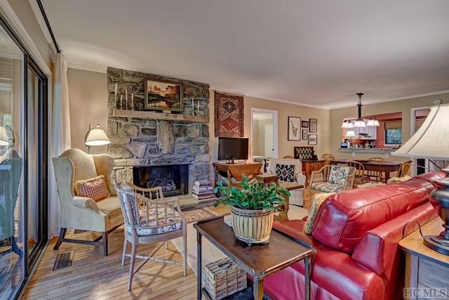 living room featuring ornamental molding, a stone fireplace, an inviting chandelier, and hardwood / wood-style floors