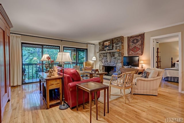 living room featuring crown molding, a stone fireplace, a wealth of natural light, and light hardwood / wood-style floors