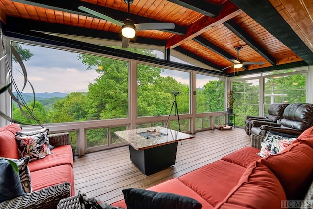 sunroom / solarium with a mountain view, ceiling fan, lofted ceiling with beams, and wood ceiling