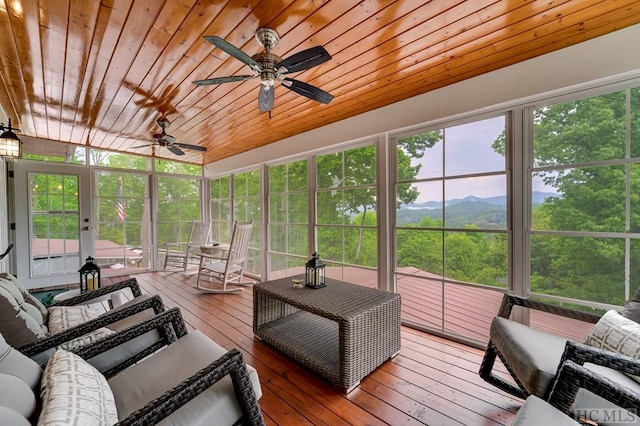 sunroom with a mountain view, wooden ceiling, and ceiling fan