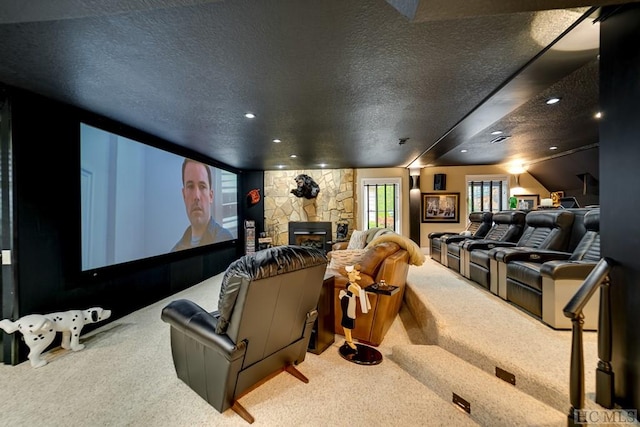 carpeted home theater featuring a stone fireplace and a textured ceiling