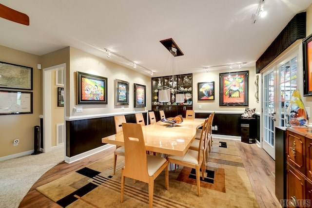 dining area featuring rail lighting, light carpet, and french doors