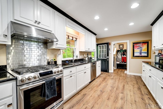 kitchen with appliances with stainless steel finishes, light wood-type flooring, tasteful backsplash, and white cabinets