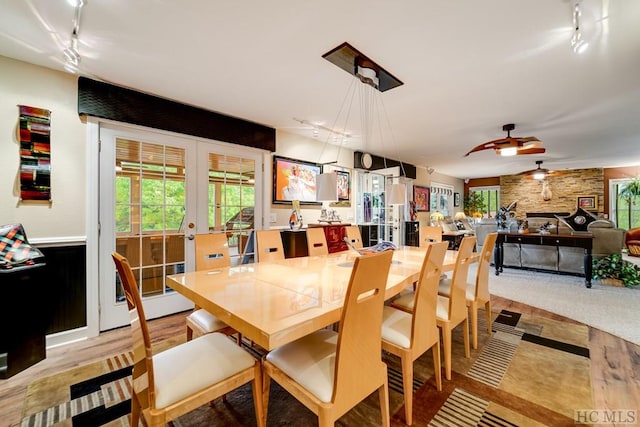 dining room with french doors, ceiling fan, rail lighting, and a large fireplace