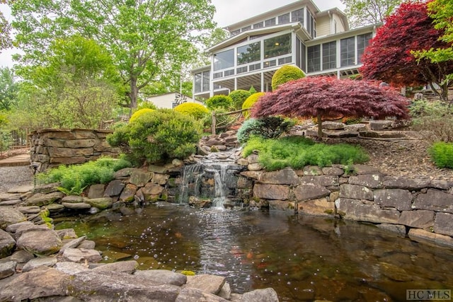 view of yard with a sunroom and a small pond