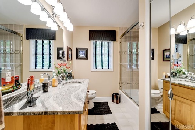 full bathroom featuring tile patterned flooring, bath / shower combo with glass door, vanity, and toilet