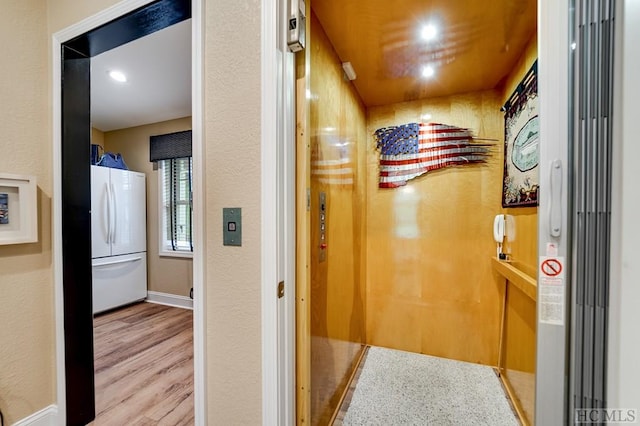 hall featuring elevator and light hardwood / wood-style flooring