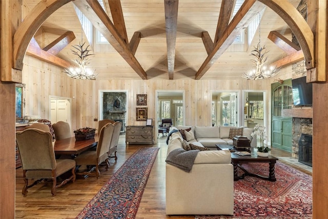 living room featuring a notable chandelier, a stone fireplace, hardwood / wood-style floors, and wood walls