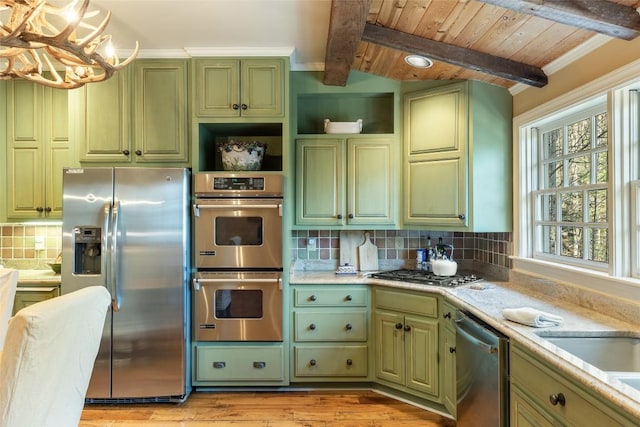 kitchen featuring decorative light fixtures, vaulted ceiling with beams, backsplash, green cabinetry, and stainless steel appliances