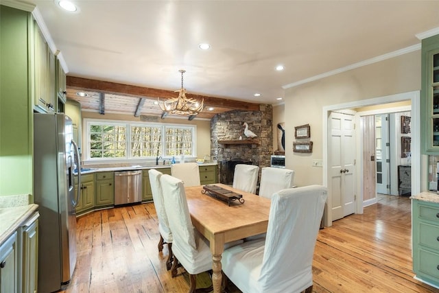 dining room featuring sink, light hardwood / wood-style flooring, beam ceiling, ornamental molding, and a stone fireplace