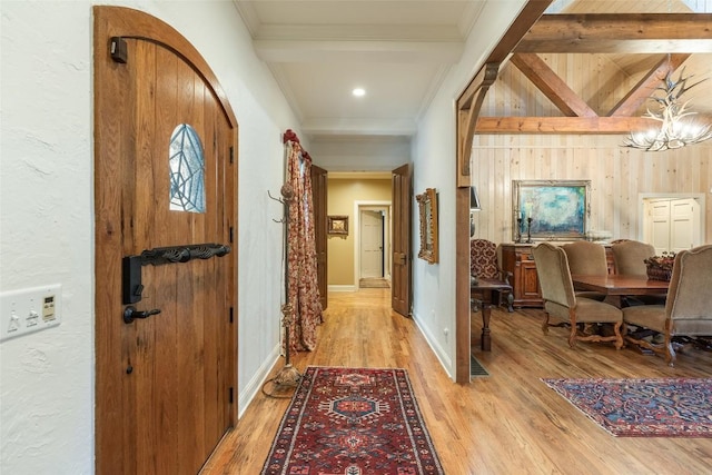 corridor featuring ornamental molding, beam ceiling, and light hardwood / wood-style floors