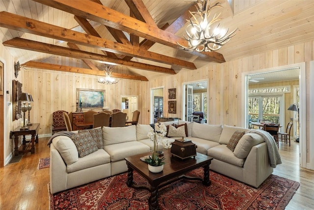 living room with wood ceiling, an inviting chandelier, vaulted ceiling with beams, wooden walls, and light hardwood / wood-style floors