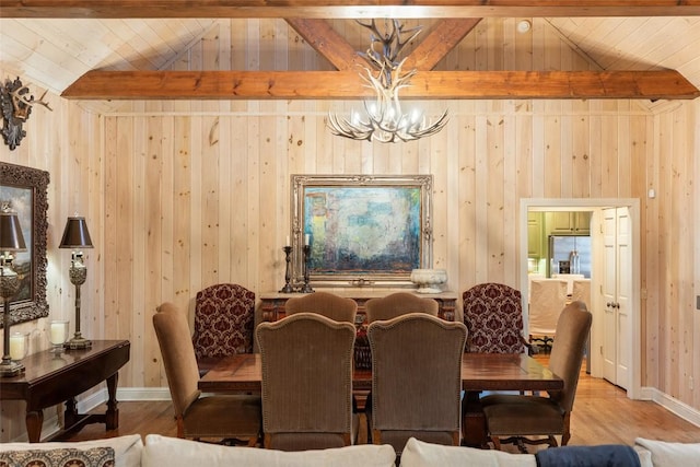 dining room with hardwood / wood-style floors, wood walls, vaulted ceiling with beams, a notable chandelier, and wood ceiling