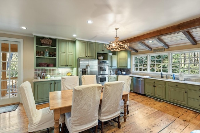 kitchen with stainless steel appliances, sink, green cabinets, and hanging light fixtures