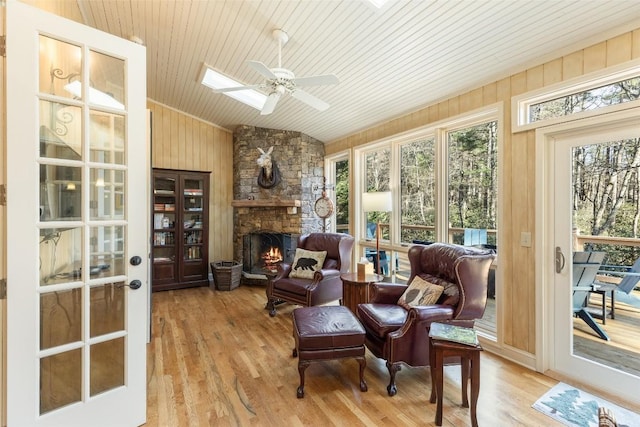 interior space with wood ceiling, ceiling fan, lofted ceiling with skylight, a fireplace, and light hardwood / wood-style floors