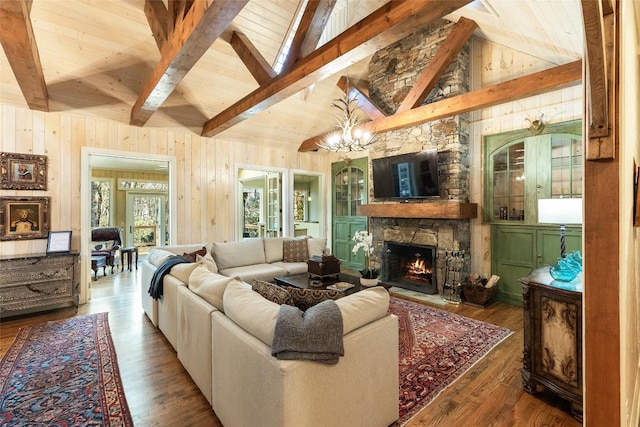 living room featuring hardwood / wood-style flooring, a stone fireplace, beam ceiling, and wood walls