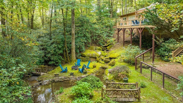 view of yard with a deck with water view and a fire pit